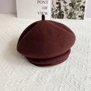 Detailed macro view of dark burgundy wool beret with silver metallic bead trim embellishment