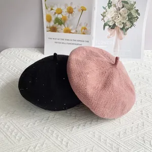 Close-up of sequined chenille beret hats in black and pink on a textured background