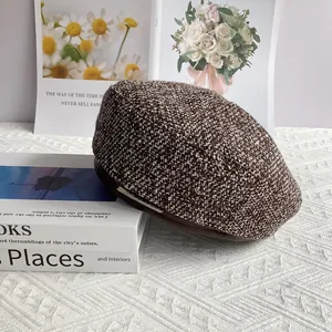 Détail du béret en tweed avec décor en métal argenté sur table avec livres d'art