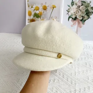 Détail de la casquette gavroche crème avec texture laine et bouton doré décoratif