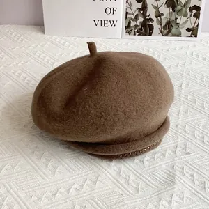 Detailed macro view of dark brown wool beret with small silver rivets on the rim
