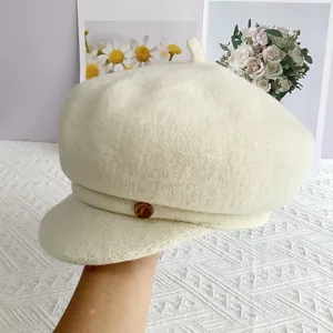 Détail d'une casquette gavroche blanc cassé en laine avec petit patch en cuir brun