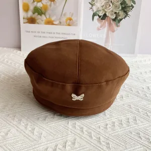 Detail of dark brown wool beret with a silver metal butterfly pin decoration