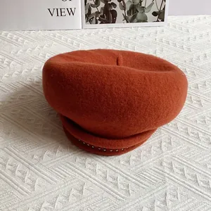 Detailed texture of orange wool beret featuring elegant silver rivet embellishments