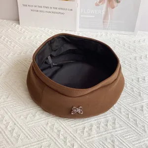 Detail view of brown wool beret featuring a silver metal butterfly buckle and black lining