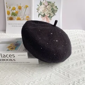 Close-up of black chenille knit beret with silver sequins on an elegant white background
