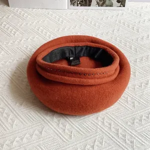 Detailed close-up of 100% wool beret texture with metal rivet decor and care label