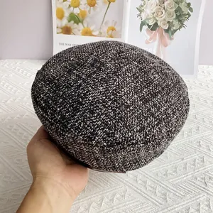 Gros plan sur la texture du tissu en tweed noir et blanc d'un béret élégant pour femme