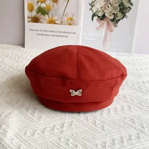 Close-up of bright red wool beret featuring a silver metal butterfly ornament