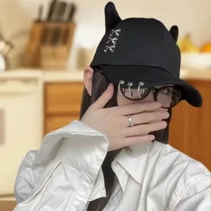 Dettaglio del cappellino punk nero con 3 anelli argentati sulla visiera e accenti 3D