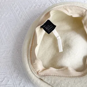 Détail de la doublure de béret en laine avec bandeau, étiquette et cordon réglable
