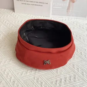 Detail of red wool beret featuring a silver metal butterfly buckle and soft inner lining