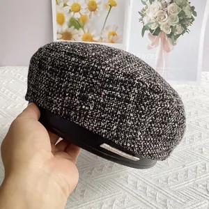 Détail du béret en tweed avec visière en cuir noir et barre métallique ornée de strass