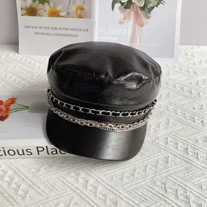 Detail of black PU leather flat top baker boy hat featuring metallic chain decorations