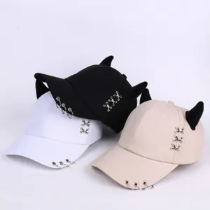 Dettaglio di cappellini hip hop con corna da diavolo e anelli in nero, bianco e beige