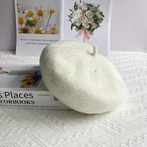 Detail of cream chenille knit beret with subtle sequins on textured white fabric