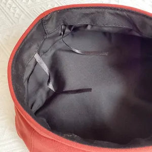 Detail of red wool beret interior with black lining and adjustable inner drawstring
