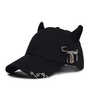 Dettaglio cappello punk nero con corna da diavolo e ciondolo a forma di lama di rasoio in metallo