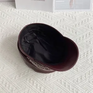 Detail of burgundy PU leather sailor cap with silver chain decoration and adjustable strap
