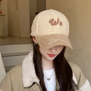 Detalle de la gorra de béisbol bicolor en borreguito con letra W bordada y textura cálida