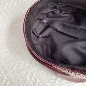 Detail of dark burgundy PU leather baker boy hat featuring adjustable drawstring and chain