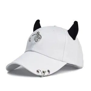 Dettaglio cappello bianco con corna da diavolo, ciondolo a stella e anelli stile punk