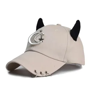 Dettaglio dei ciondoli a luna e stella argentati sul cappellino da baseball kaki