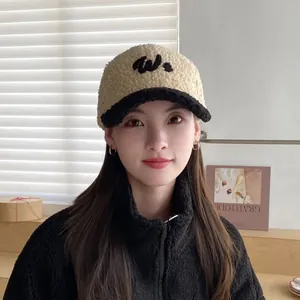Detalle de gorra de béisbol bicolor de felpa con logotipo bordado sobre una modelo