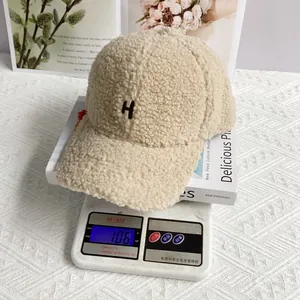 Detail view of beige lamb wool baseball cap with H embroidery on a scale weighing 106g