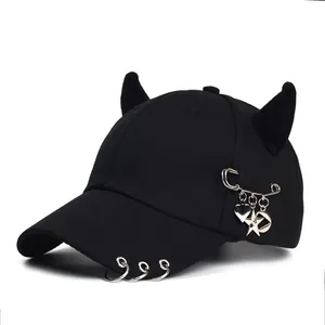 Dettaglio cappello punk nero con corna 3D e ciondolo a cuore sulla visiera