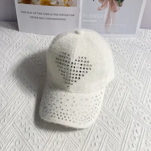 Detail of white plush baseball cap with rhinestone heart and sparkling brim texture