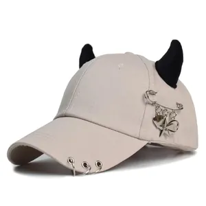Dettaglio del cappello beige con corna nere, anelli argento e ciondoli in stile punk