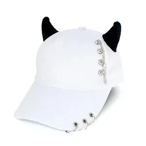 Close-up of white baseball cap with black devil horns and silver punk metal chains