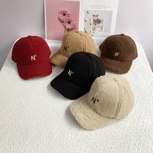 Detailed embroidery of letter N on teddy fleece baseball caps in various colors