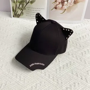 Detail of black punk style baseball cap with cat ears, silver rivets and white embroidery