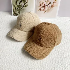 Close-up of fluffy fleece baseball caps with H embroidery and warm fuzzy texture