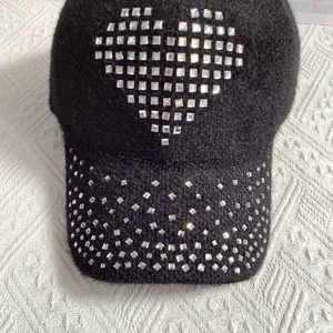 Detail of black faux fur baseball cap with sparkling rhinestone heart and warm texture