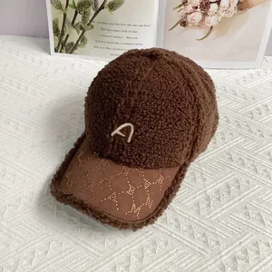 Detail der braunen Plüsch-Basecap mit Buchstaben-Stickerei A und Pailletten-Schirm