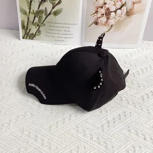 Detail of punk style baseball cap with metal rivets, cat ears and white letter print