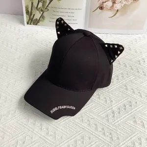 Detail of punk style black baseball cap featuring 3D cat ears with silver metal rivets
