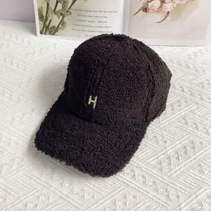 Close-up of black fleece baseball cap featuring a golden H letter buckle decoration