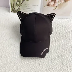 Detail of black punk style baseball cap with cat ears, silver studs and white text print