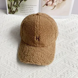 Detailed close-up of brown sherpa fleece baseball cap with embroidered H letter
