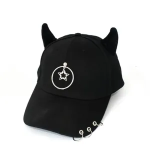 Dettaglio cappello nero con corna da diavolo in peluche e ciondoli in metallo argento