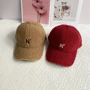 Close-up of camel and burgundy fleece baseball caps with embroidered 'N' lettering
