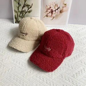 Close-up of beige and burgundy sherpa baseball caps with high-quality letter embroidery