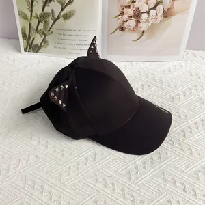 Detail of punk style black baseball cap featuring silver studded cat ears and lettering