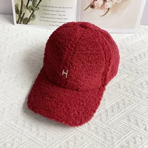 Detail of dark red lamb wool baseball cap featuring a white embroidered letter H
