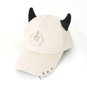 Dettaglio del cappello beige con corna di demone nere e ciondolo a stella in argento