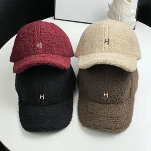 Detail of four faux lamb wool baseball caps with embroidered H letter in various colors